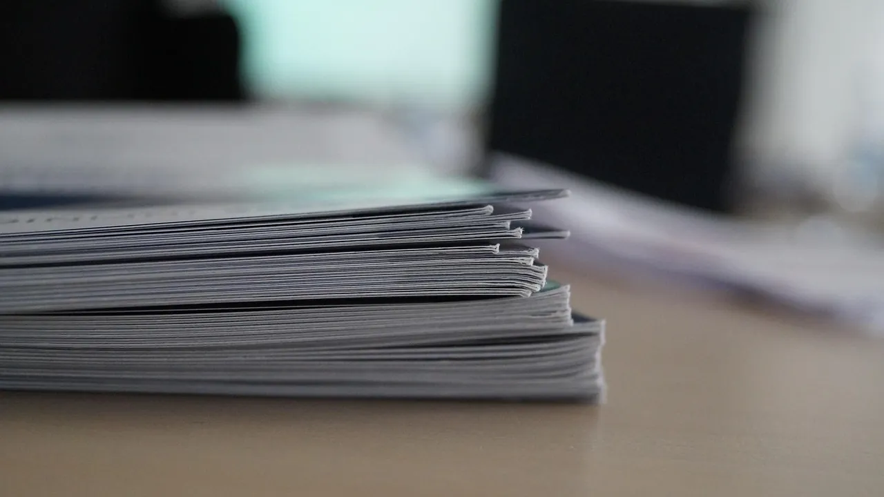 Pile de documents agrafés posée sur une table, en faible profondeur de champ.
